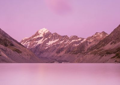 Lake in the middle of the mountains with Mt Cook reflection during a pink sunset