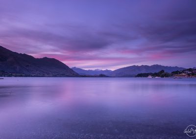 purple sunet on a lake with mountains in the background in Tekapo