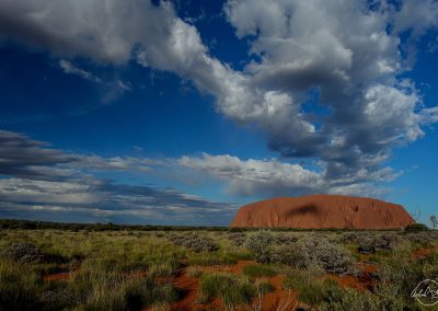 Uluru mountain with blue sky and large white clouds