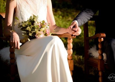 Groom and bride with a tatoo holding hands during wedding ceremony in the garden