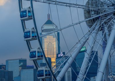 Zoom on hong kong big wheel with tower and buildings in the background at dusk