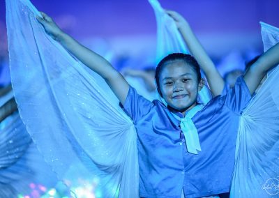 Young girl performing on stage with blue wings and blue lights