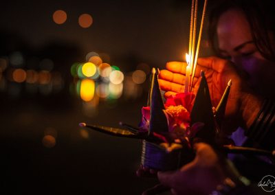Hands holding flowers and candles at night for loy kratong