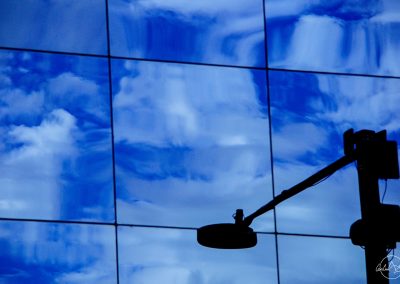Reflection of a black street lamp in a blue glass building