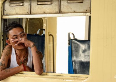Man at the window of a train in Myanmar with body covered with tatoos