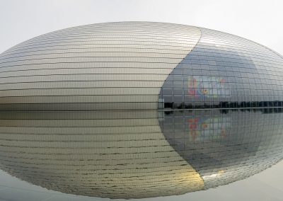 Oval building of the National Centre for the Performing Arts reflected in the water in daytime