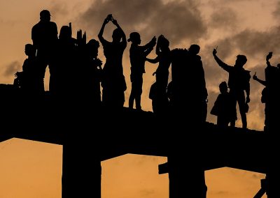 Silhouette of a group of people on a bridge at sunet taking pictures and selfies with their phones