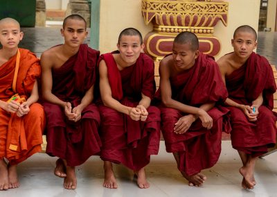 5 teenage monks sitting on a bench in a temple in Bagan