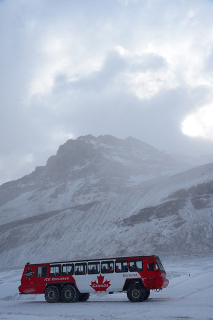 Red bus on a glacier, with a mountain in the background and in the snow