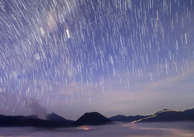 Stars rain above volcano in a dark blue sky